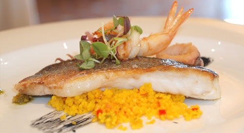 Lubina plancheada con base de cous cous, chopitos y mojo verde